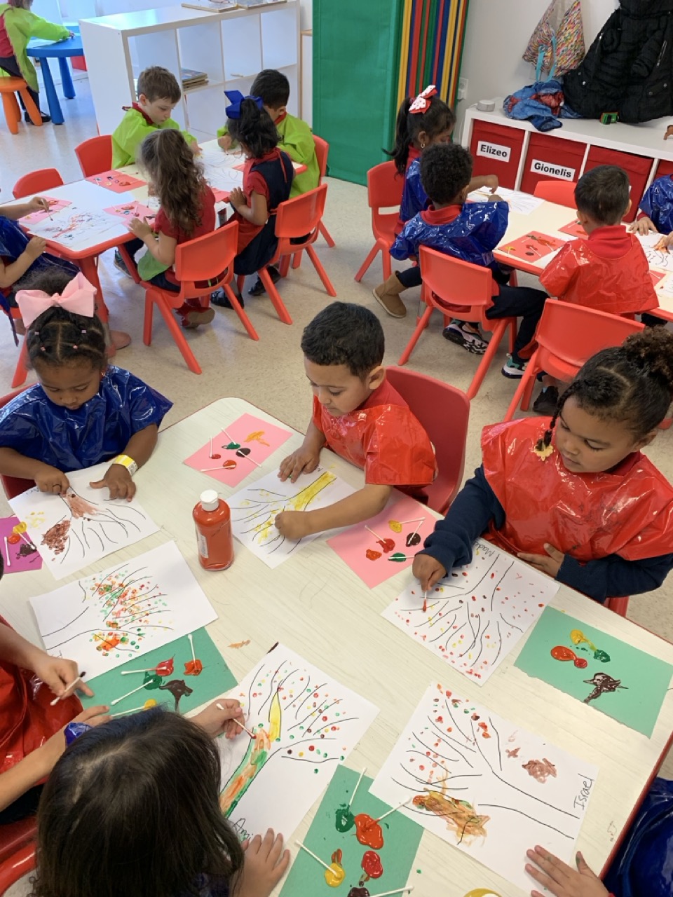 Children painting fall trees together at activity tables at Malave Child Care Center