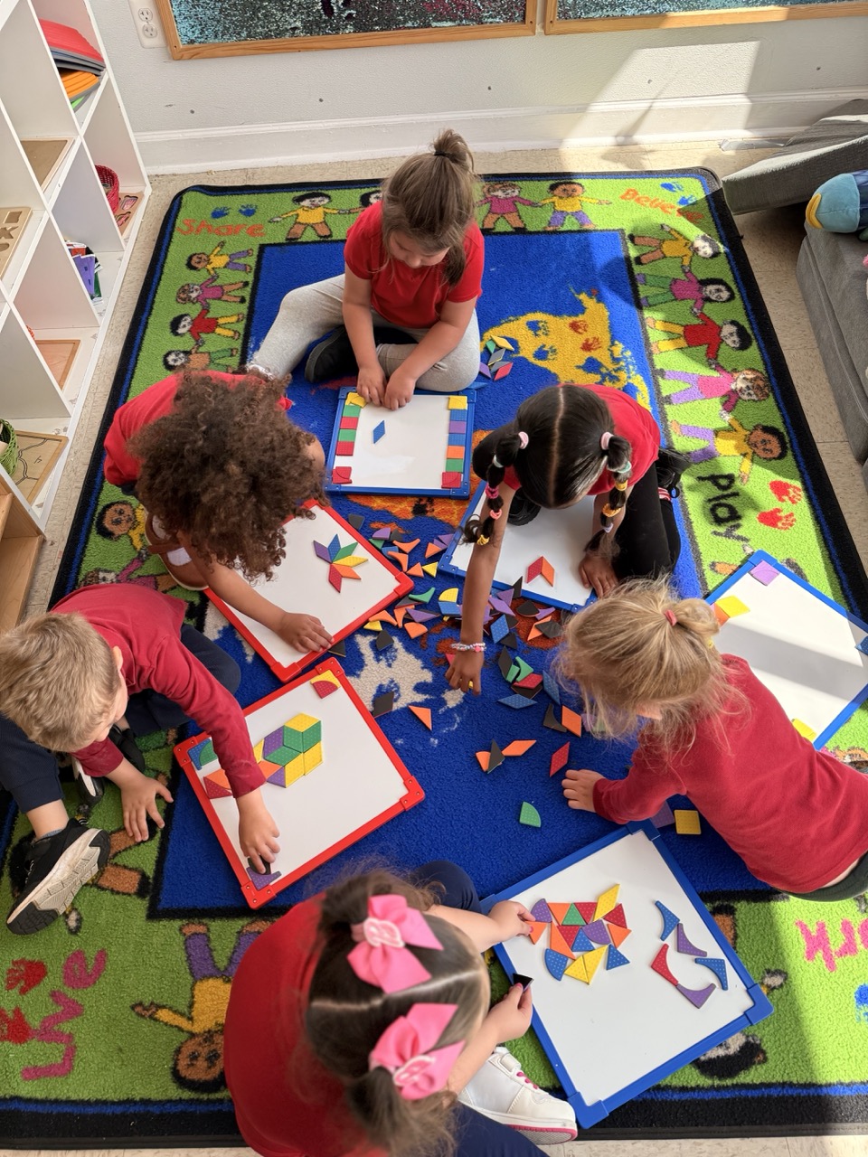 Children building with colorful pattern blocks together on the classroom rug