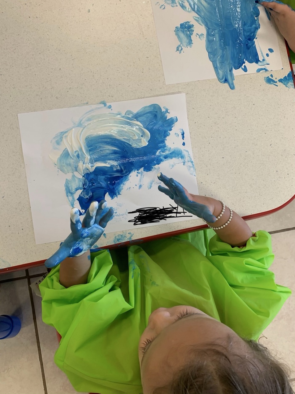 Un niño pequeño explorando pintura de dedos azul durante una actividad creativa