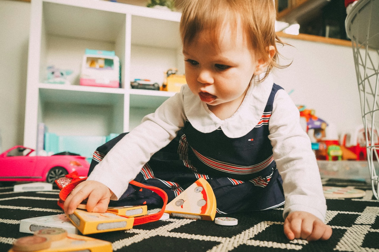 Toddler working with a wooden puzzle on the classroom rug