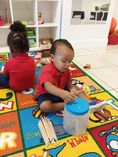 Toddler playing on a colorful alphabet rug in the classroom