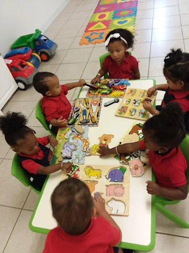 Toddlers working together on wooden puzzles at a classroom table